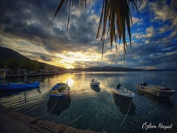 Sailboats moored on sea against sky during sunset