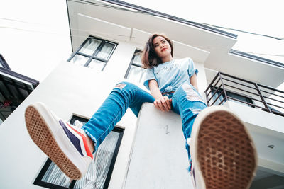 Low angle view of young woman sitting outdoors