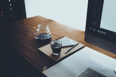 Coffee glass by computer on table