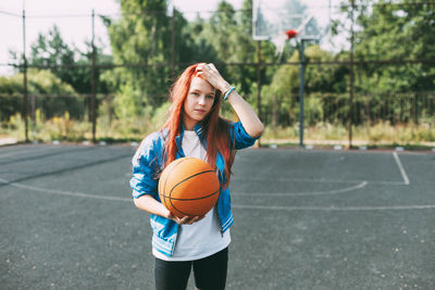 Portrait of a smiling teenage girl with a basketball on the sports field. sports, health, lifestyle