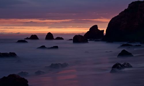 Rocks on sea against sky during sunset