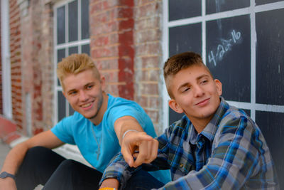 Young man sitting with friend outdoors