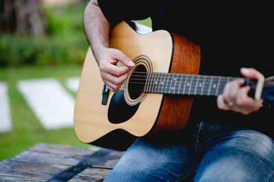 Midsection of man playing guitar