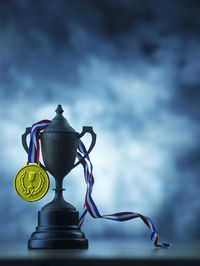 Close-up of rusty trophy and medal against sky