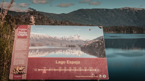 Information sign by lake against mountains