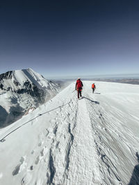 Roped party descending mont blanc under dark blue sky during high wind