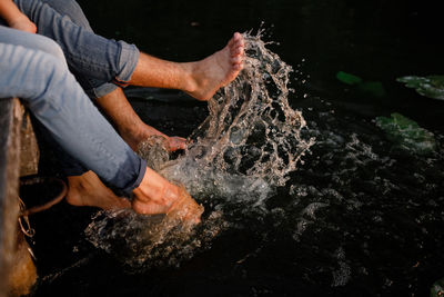 Low section of couple splashing water in lake