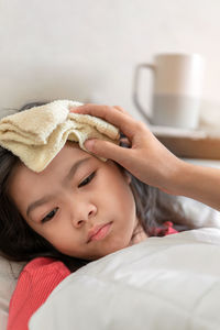 Close-up portrait of baby girl lying on bed at home
