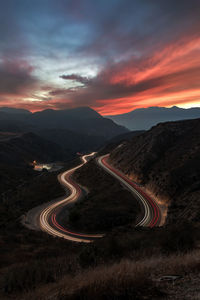 High angle view of light trails on mountain road against sky at sunset