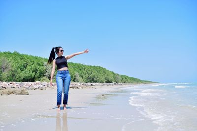 Full length of man standing on beach against clear sky