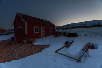 House on snow against sky at night