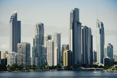 Sea by city skyline against sky