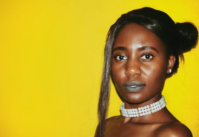 Portrait of young woman against yellow background