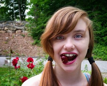 Portrait of teenage girl eating cherry at park