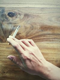 Close-up of hand holding cigarette on table