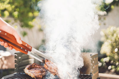 Hand holding meat on barbecue grill