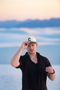 Portrait of young man standing against sea