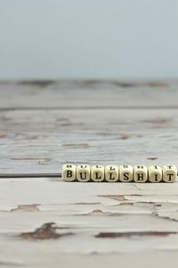 Close-up of text on wood at beach against sky