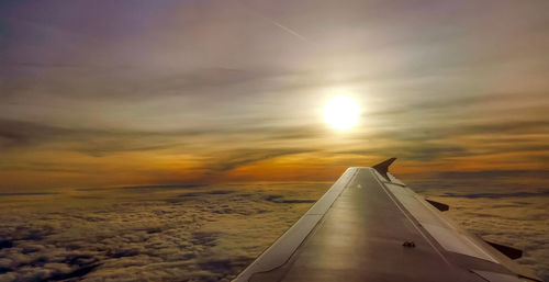 Airplane wing against sky during sunset