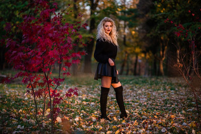 Full length portrait of young woman standing on street during autumn
