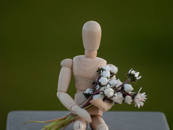 Close-up of figurine with flowers on retaining wall
