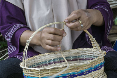 Midsection of woman making wicker basket