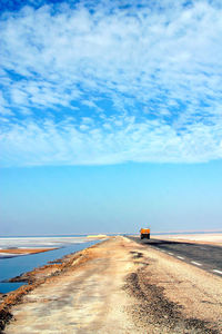 Road by sea against blue sky