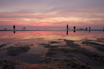 Silhouette man standing on beach against sky during sunset