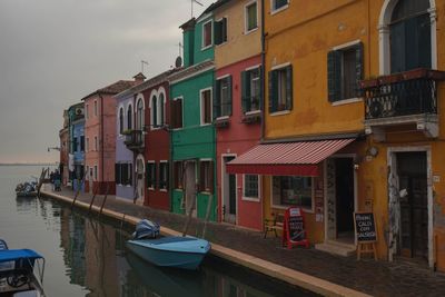 Boats moored in canal by buildings in city