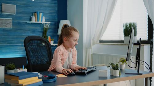 Side view of woman using mobile phone while sitting on table