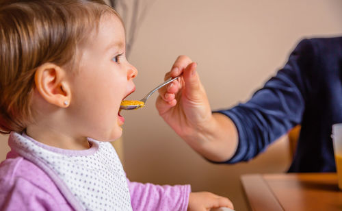 Close-up of mother feeding baby girl food 