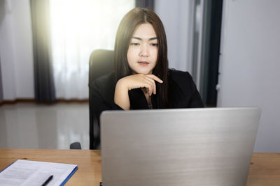 Young woman using mobile phone while sitting on table