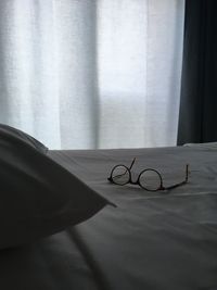 Close-up of eyeglasses on bed against window