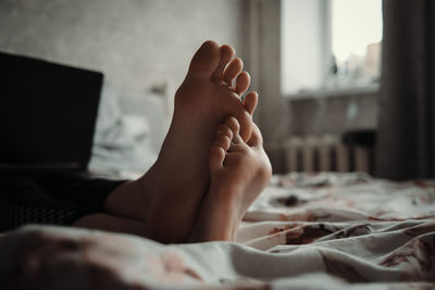 Midsection foot of woman lying on bed