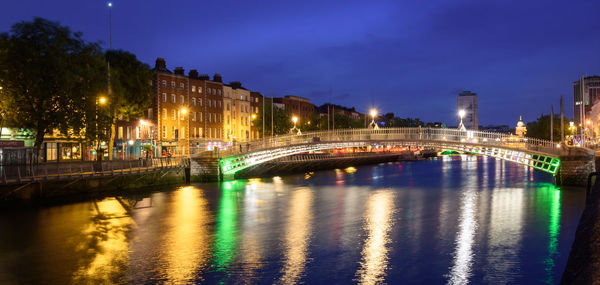 Illuminated bridge over river at night