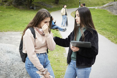 Rear view of woman using mobile phone in park