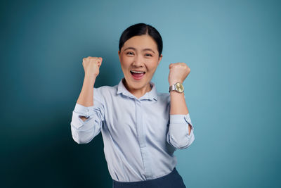 Portrait of a smiling young woman against blue background