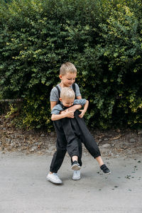 Two brother kids siblings play together near house. two little boys embrace brotherly and having 