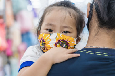 Mother carrying daughter wearing mask at supermarket