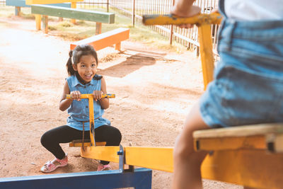 High angle view of friends playing on seesaw at playground