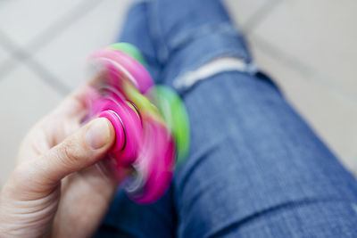 Midsection of person spinning pink fidget spinner