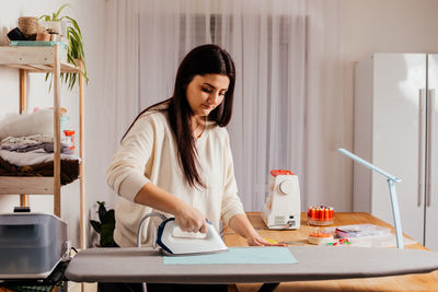 Young woman looking down while standing on table at home