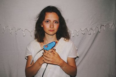 Portrait of young woman standing against wall at home