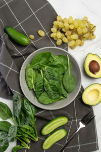 Gray culinary background with ingredients for green salad. spinach with avocado and grapes.