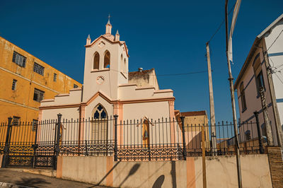 Facade of small church and belfry behind iron fence, in a sunny day at são manuel, brazil.