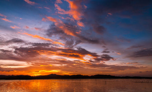 Scenic view of dramatic sky over lake during sunset