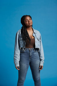 Portrait of beautiful young woman standing against blue sky