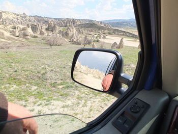 Reflection of man on side-view mirror of car