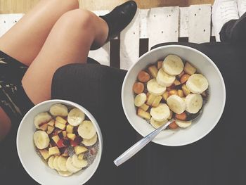 Low section of woman with fruit bowls on sofa