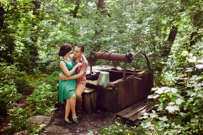 Full length of happy woman standing against trees